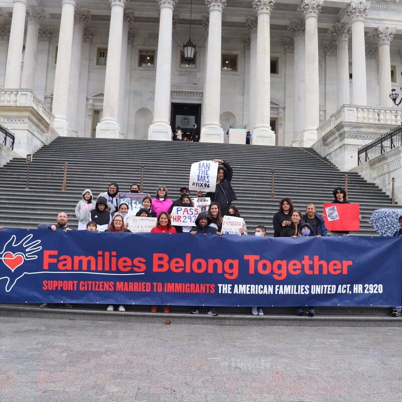 This is an image of people holding a long sign that reads, "Families Belong Together".